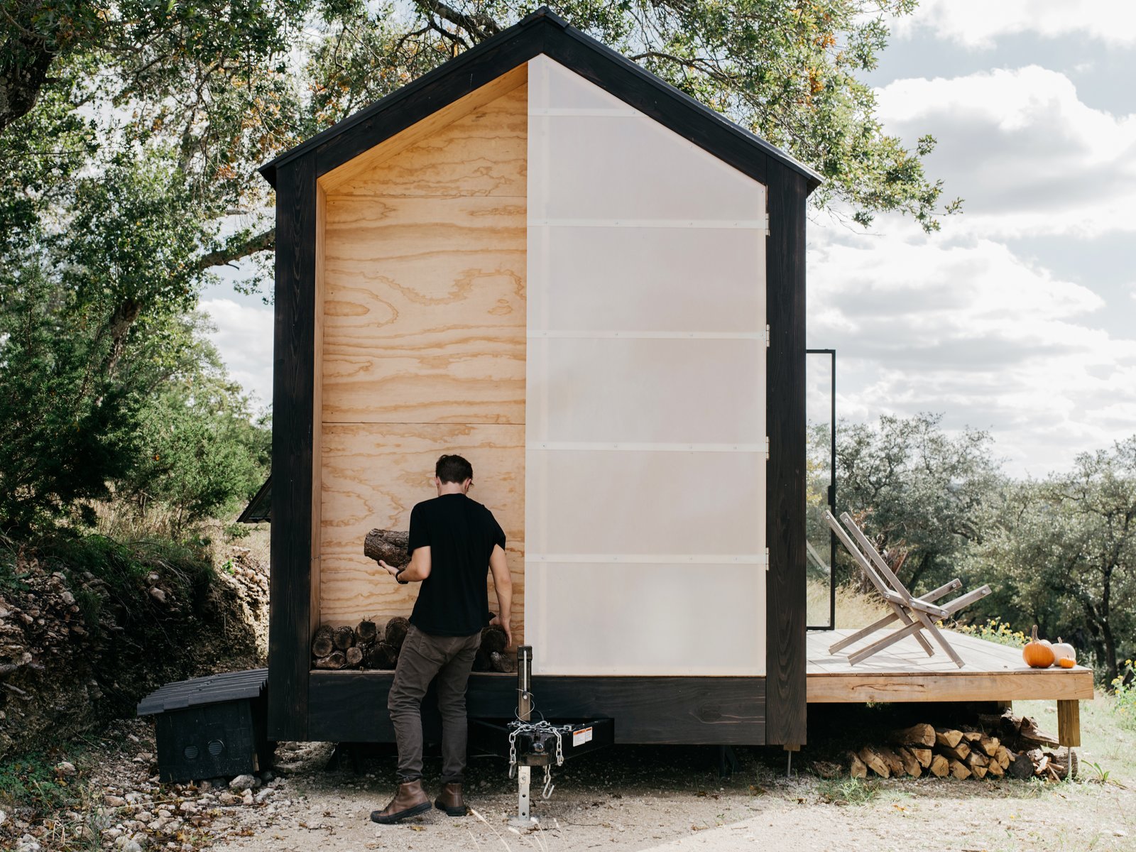 A fiberglass door covers a void in the wall that holds a solar-powered water heater, a propane tank, and wood for a fire bowl.